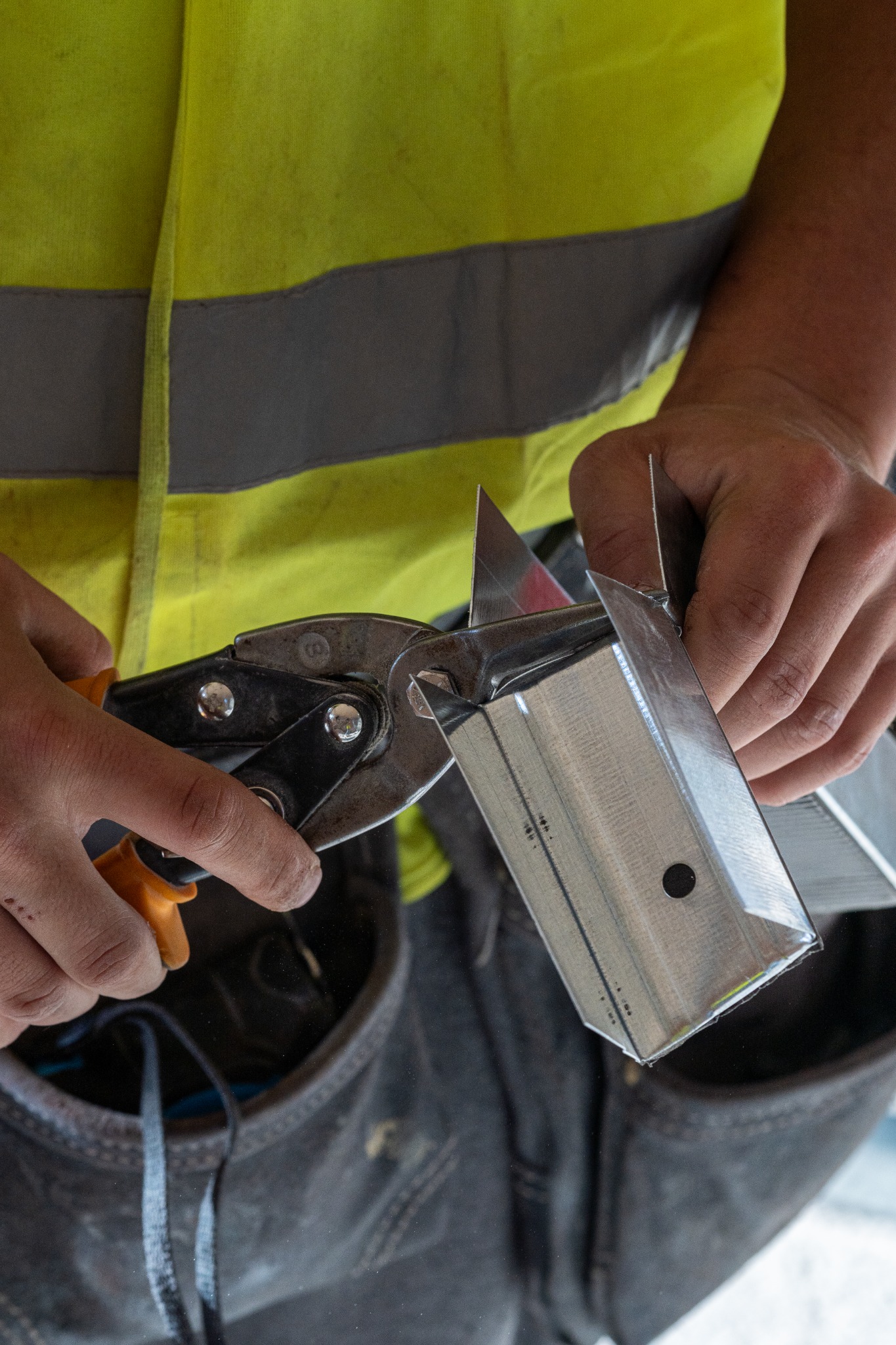 Close-up of hands cutting a metal section
