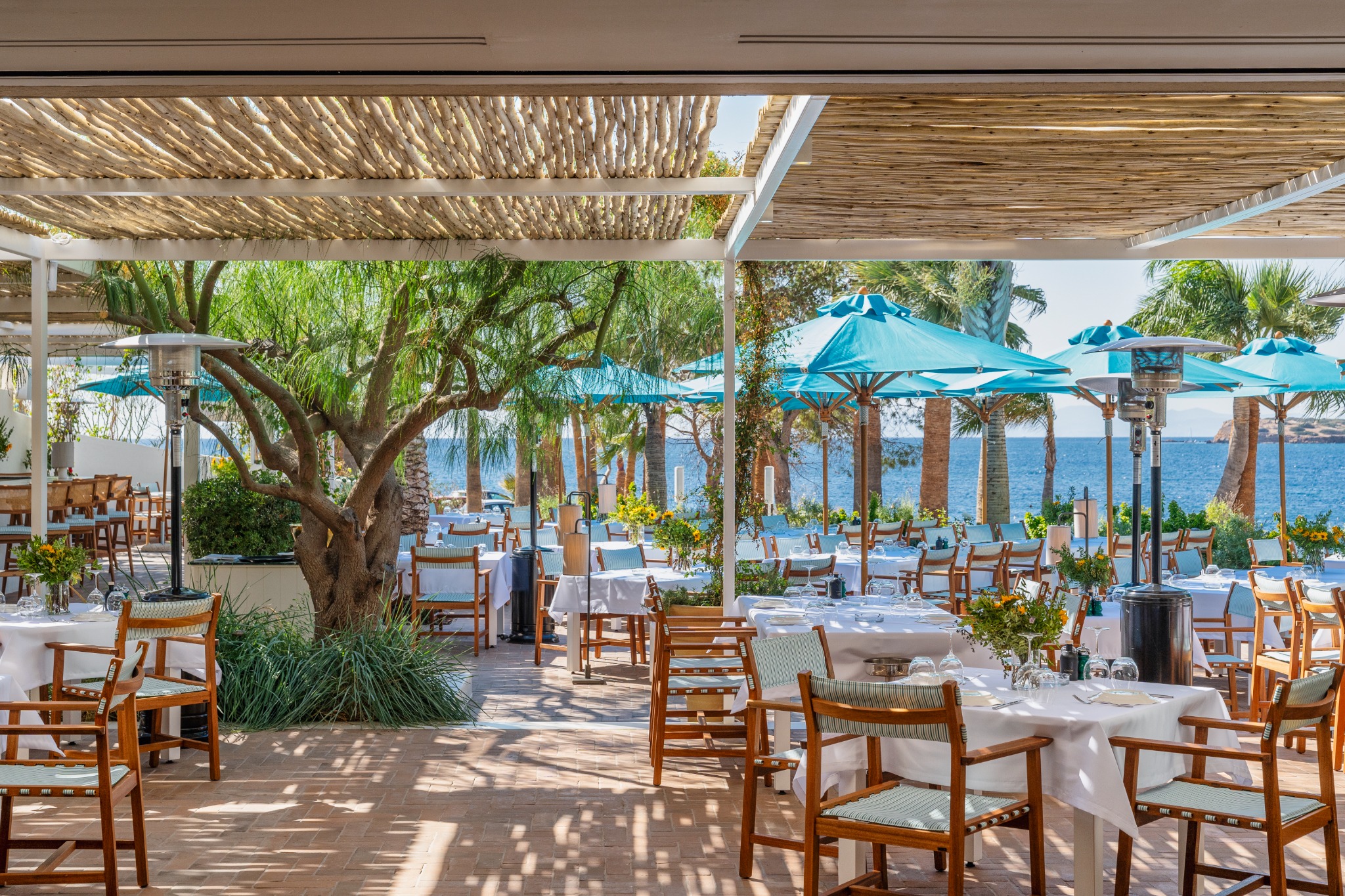 Sea Satin Athens, Voula — daytime outdoor dining with blue umbrellas and sea