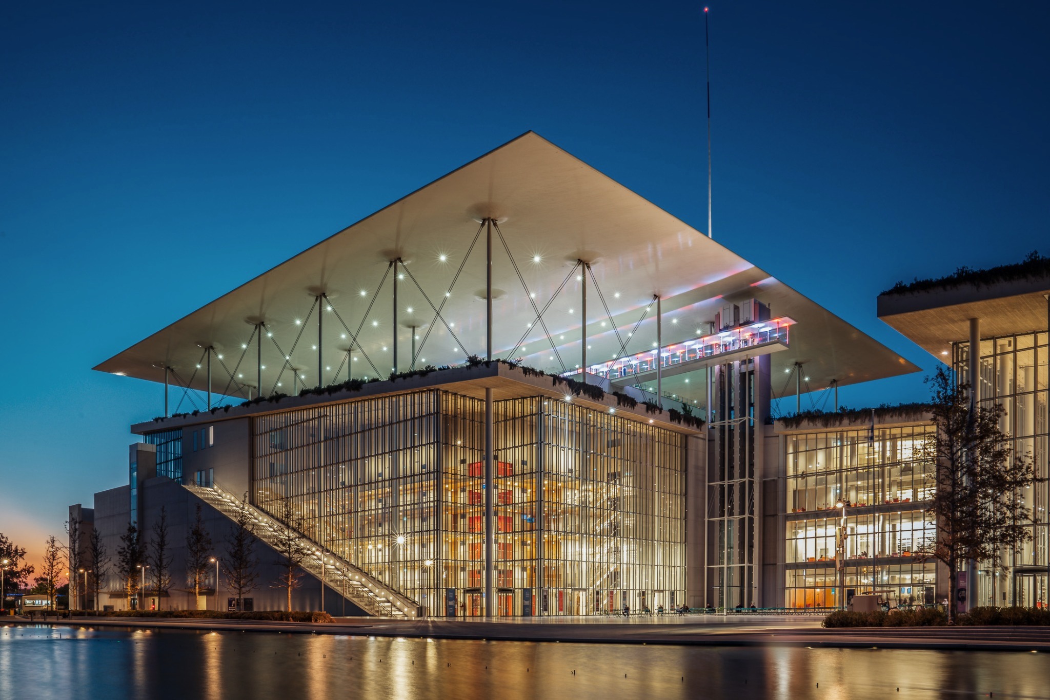 Stavros Niarchos Foundation Cultural Center — illuminated glass facade and canopy at dusk