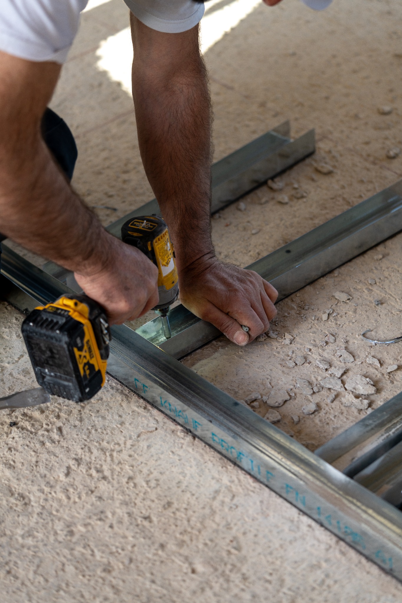 Worker drilling and fastening a steel track